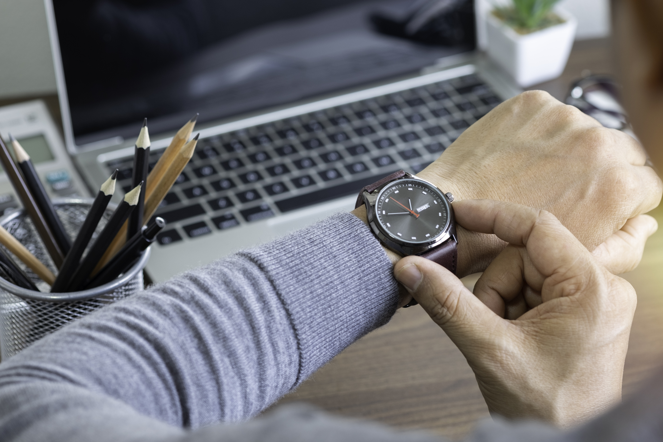 Man checking watch while at desk with laptop.