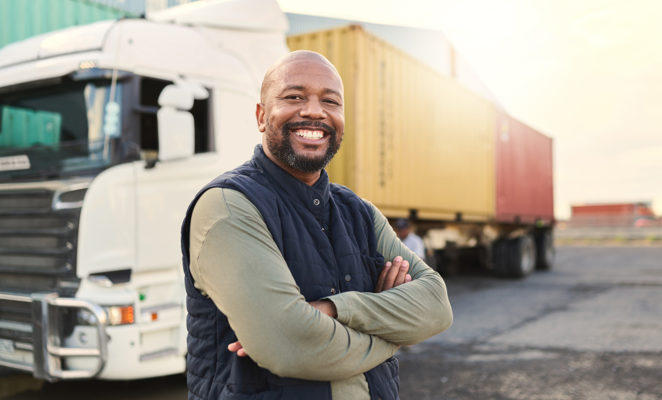 Truck driver standing outside in front of his truck and trailer.