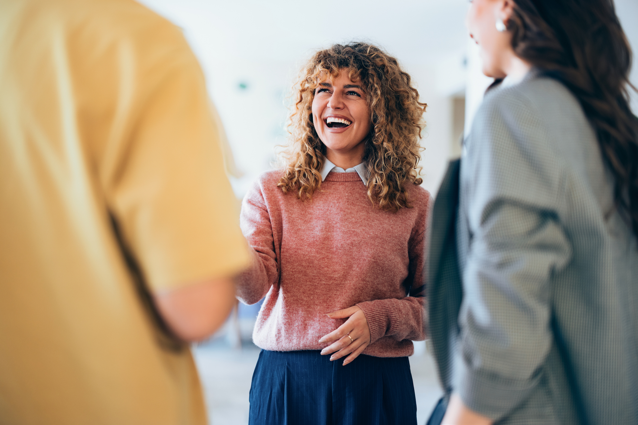Woman in office setting shaking hands with colleagues.