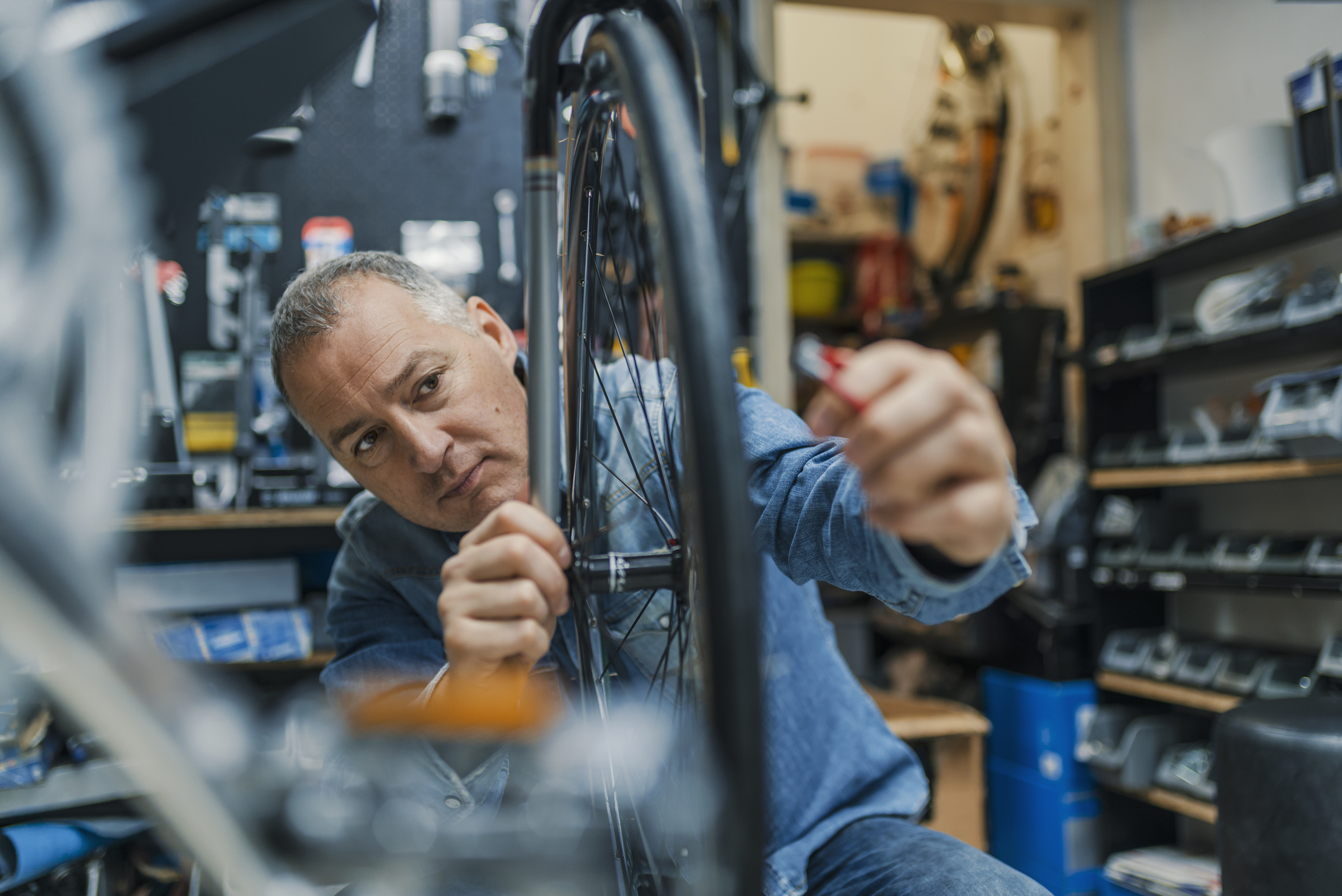 Middle-aged man working on a bicycle in a bike shop.